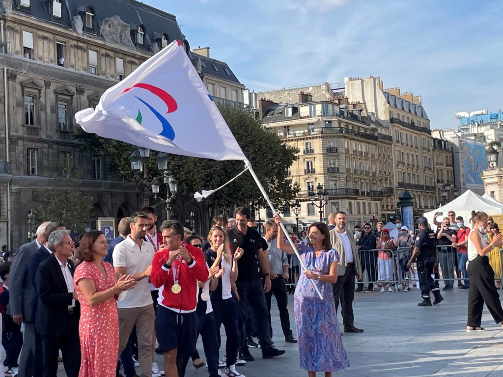 La maire de Paris, Anne Hidalgo, portant le drapeau des Jeux Paralympiques lors de la cérémonie organisée pour le retour des médaillés de Tokyo 2020 et la passation avec Paris.